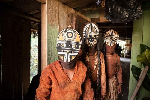 Macedonia, Colombia, Mar 05, 2009: Three young boys wear their traditional Miraña tribe costume, in the occasion of a performance for tourists at Macedonia, a small riparian village in the Colombian part of the Amazon River. Native people are gradually losing their identity over the years, through alcoholism, drug abuse, and violence. People try to make a living working in the few jobs that are available in the village apart from tourism.